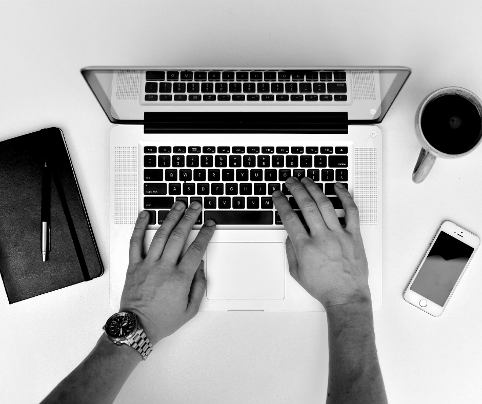 Man writing on Macbook with coffee and notepad